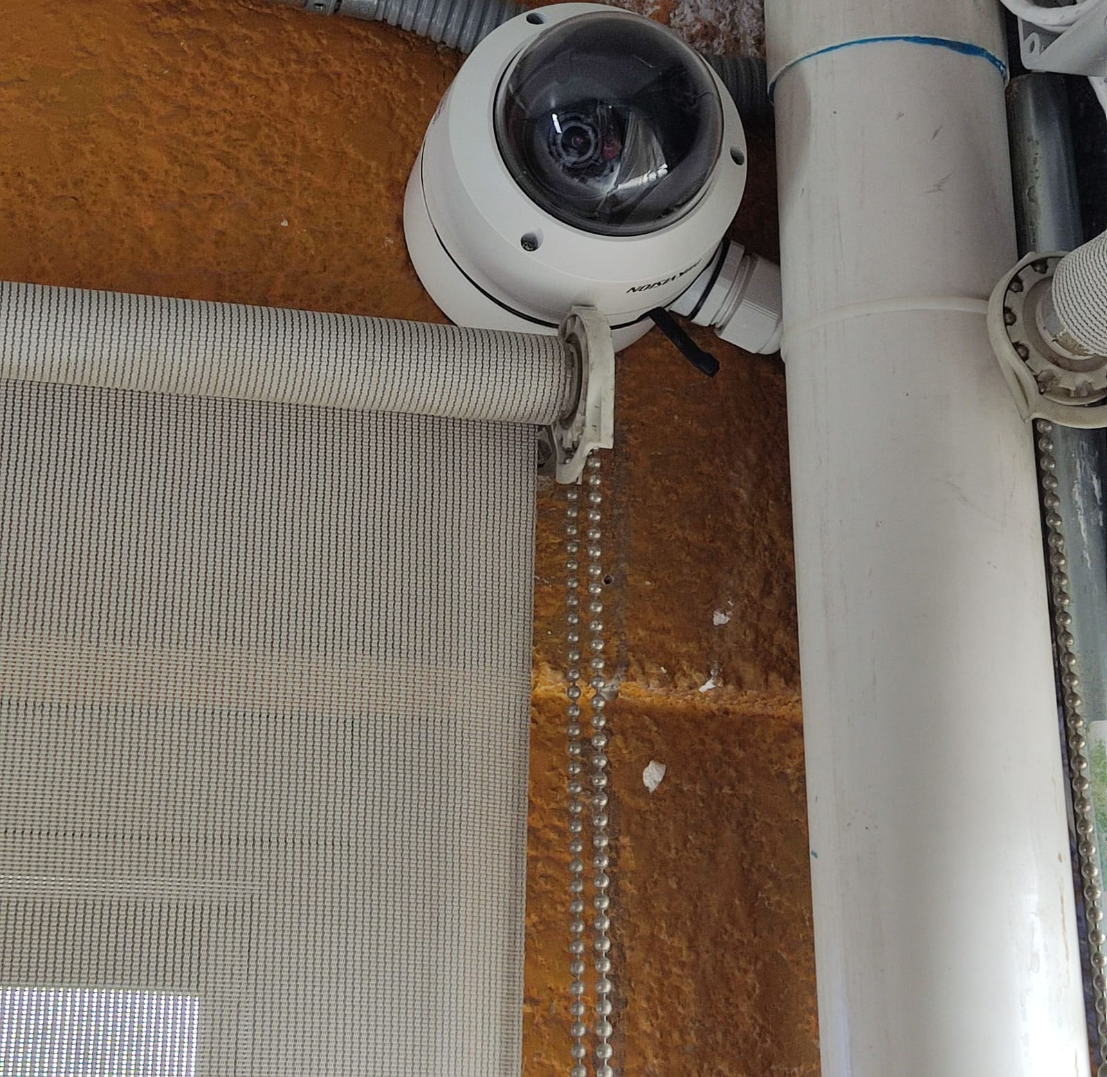 Domo Hikvision en pared naranja con canalización de tubería protegida