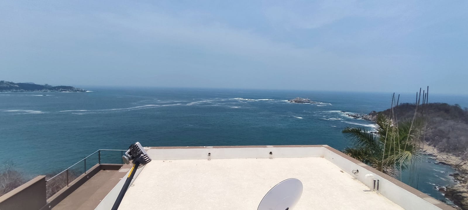 Azotea costera con vista panorámica al mar y la parte trasera de una antena satelital en primer plano