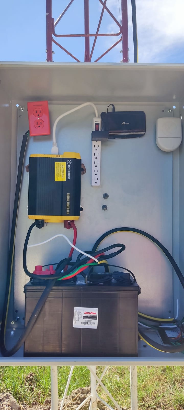 Gabinete de energía a la intemperie con inversor, batería y router en la base de una torre