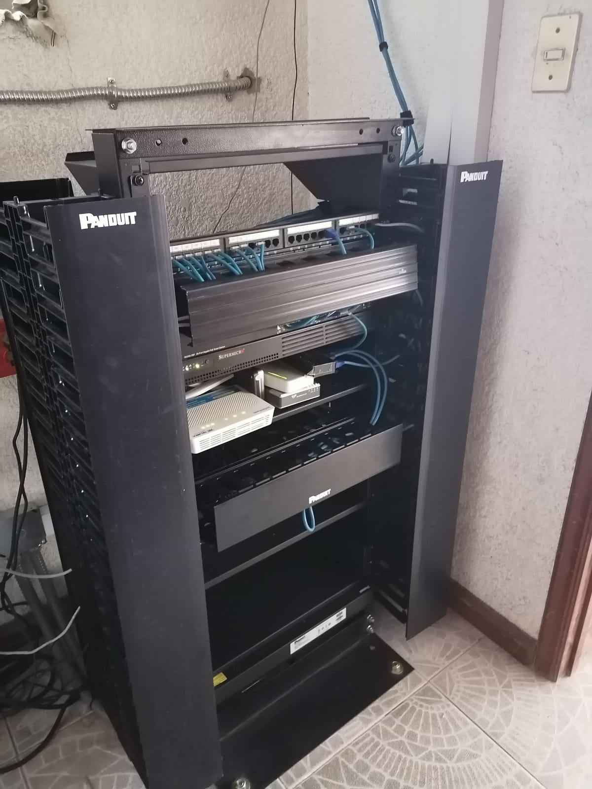 Rack abierto marca Panduit con patch panel y cableado de red peinado en un cuarto de telecomunicaciones