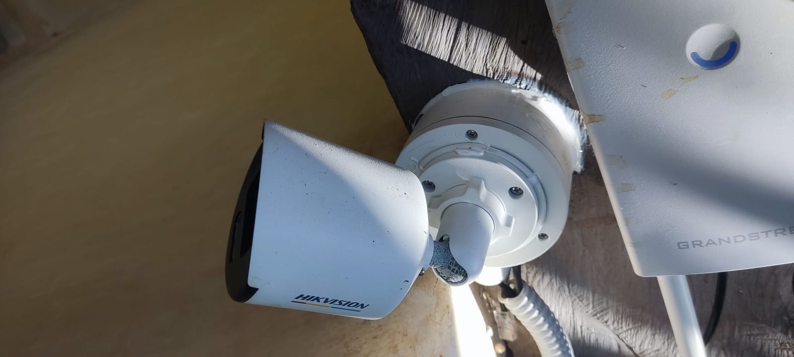 Cámara Hikvision y access point Grandstream instalados juntos sobre un poste de madera